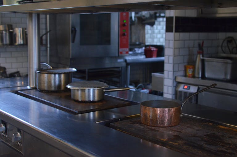 Stainless steel pots on a kitchen counter in a professional restaurant setting.