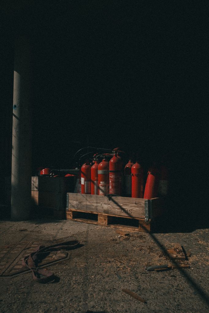 A collection of red fire extinguishers in dark industrial area, Copenhagen.